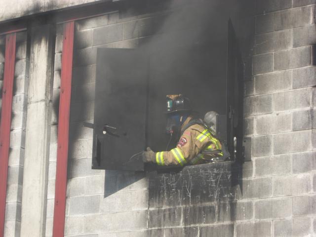 Firefighter Andy McCullin opens a window to ventilate the burn building.